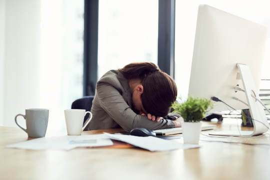 a woman professional at desk with head on the desk