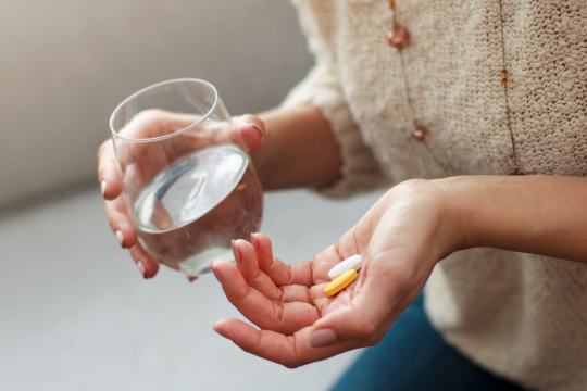 Woman taking vitamins with a glass of water
